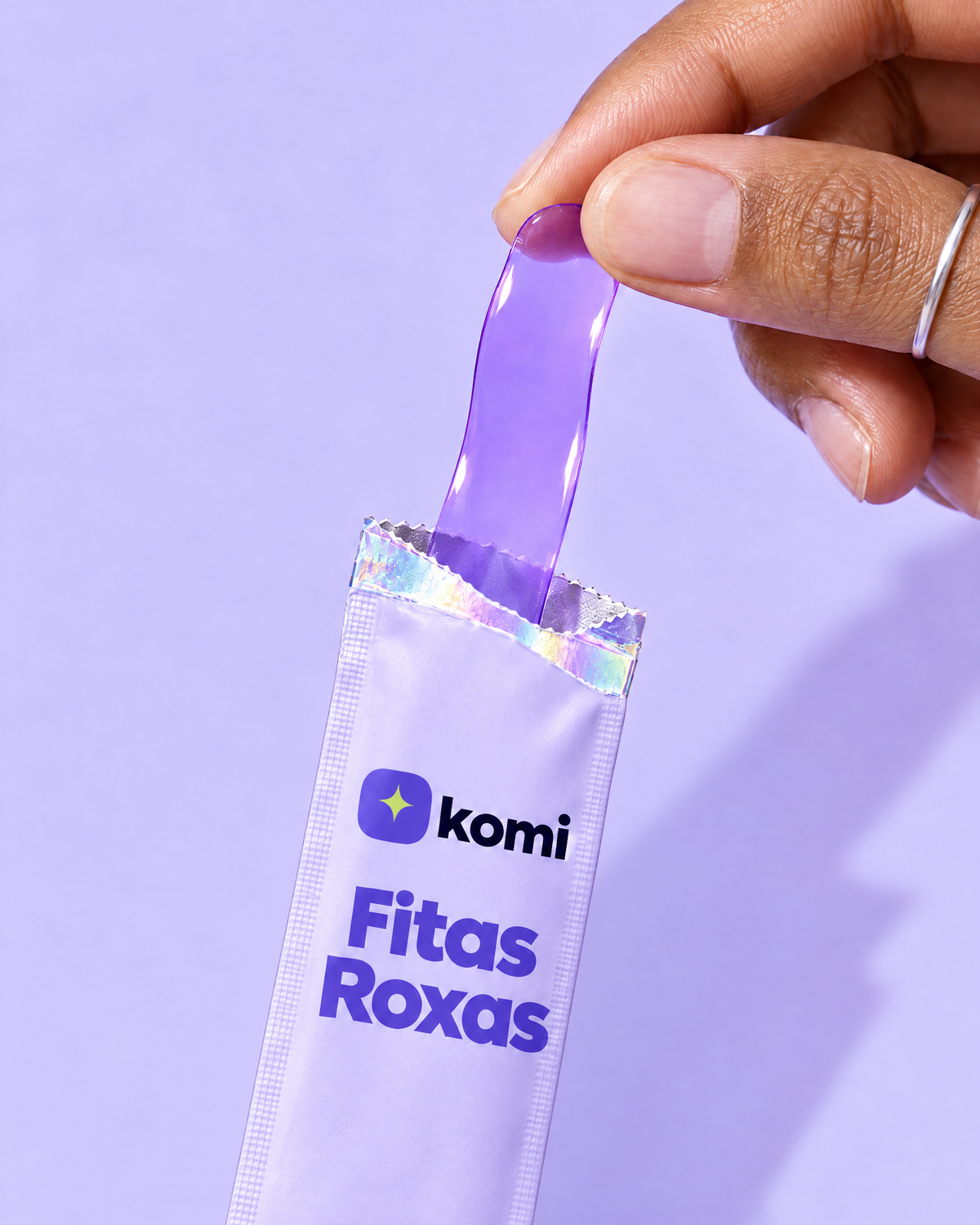 Fita roxa fina e translúcida saindo do sachê das Fitas Roxas, na mão